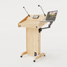 Right side view of Lectern 1. Showing gooseneck mics, touch screen controller, laptop arm and tray, lower audio visual connection plate. Natural grain with expressed plywood edge.